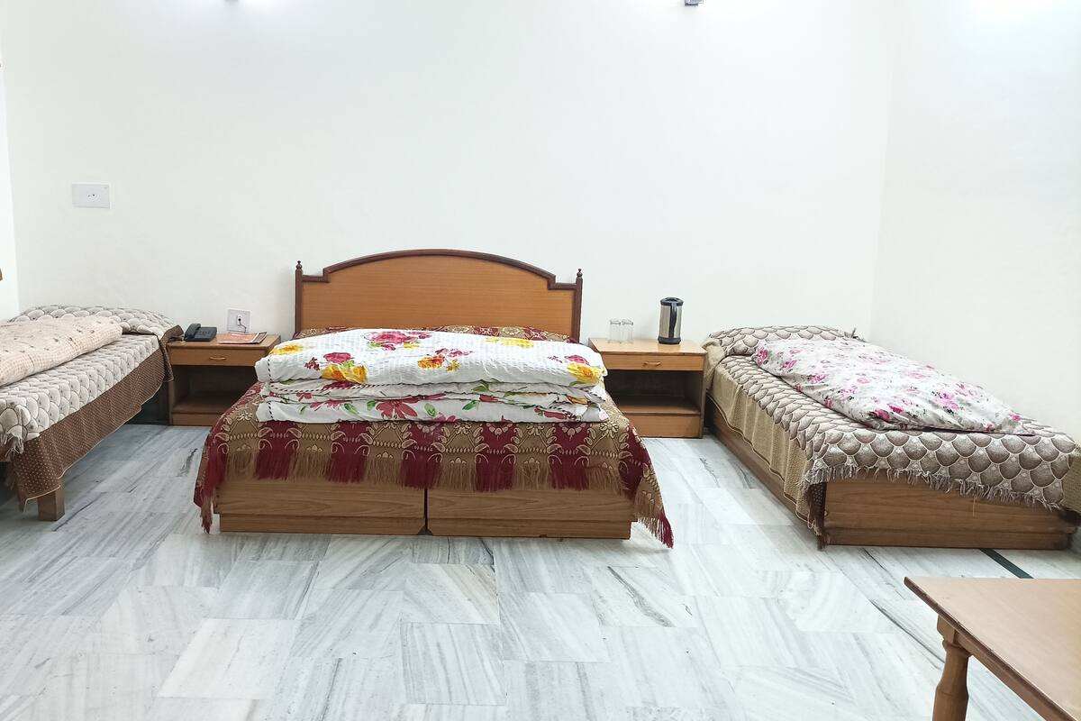 A bedroom with a wooden bed, two bedside tables, a TV, and a small table.