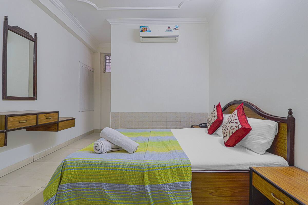 A neatly arranged bedroom with a bed, bedside table, and a wall-mounted air conditioner.