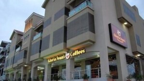 A multi-story building with a storefront labeled "Gloria Jean's Coffees." - Lovely 2-bed Apartment in Rawalpindi (Rawalpindi)
