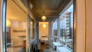 Ein schmaler Balkon mit einem Bett, einem Sessel und einem Tisch.