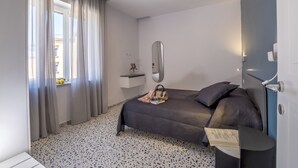 Une chambre à coucher moderne avec un lit, une table de chevet, un miroir et une fenêtre avec des rideaux.