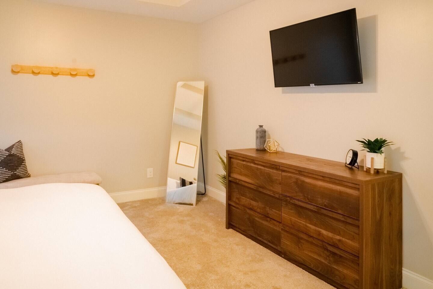 Une chambre à coucher avec un lit, une commode, une télévision et un miroir.