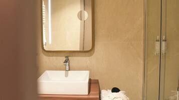 A modern bathroom with a large mirror, a sink, and a glass shower enclosure.