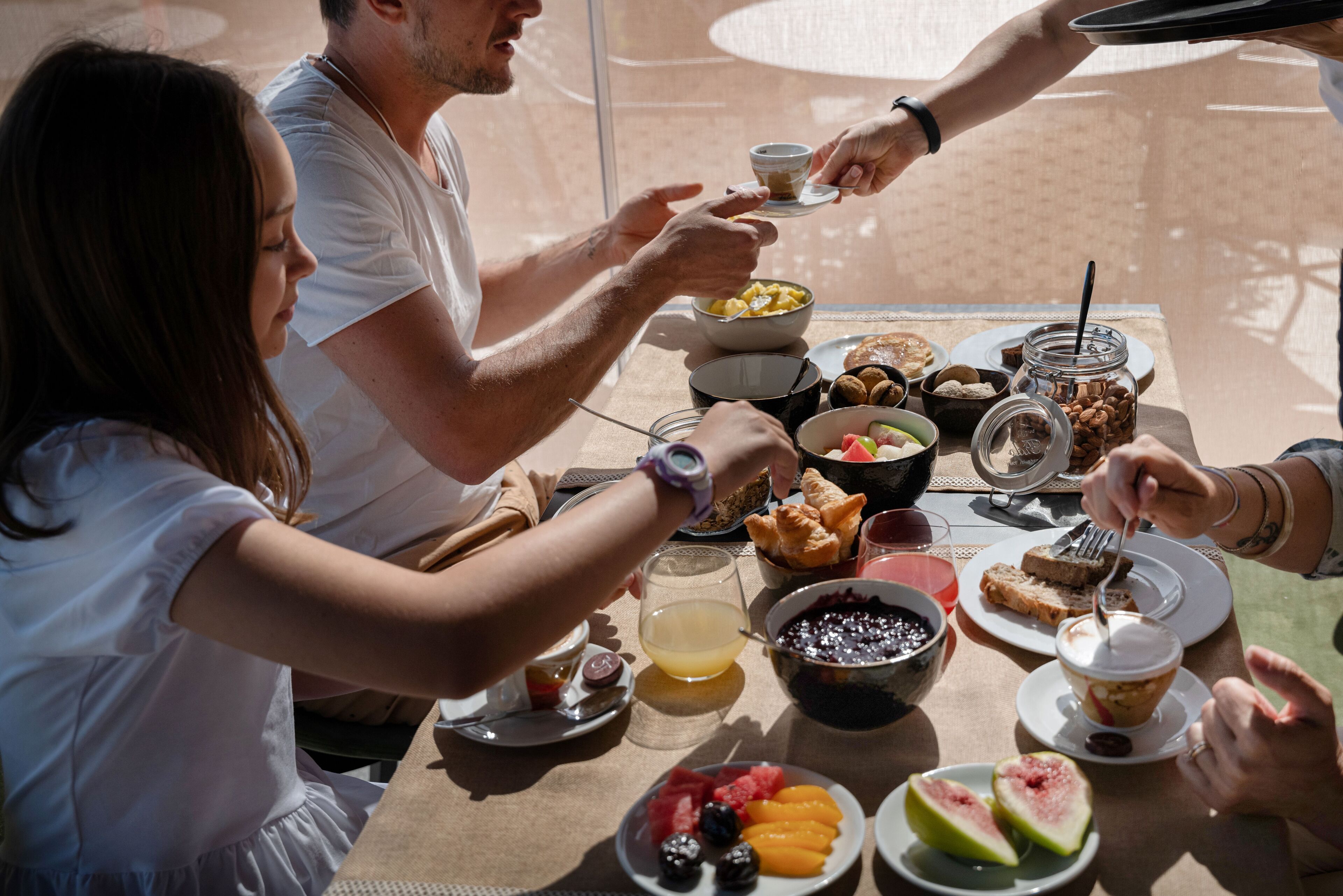 Un grupo de personas desayunando en una mesa con diversas comidas y bebidas.