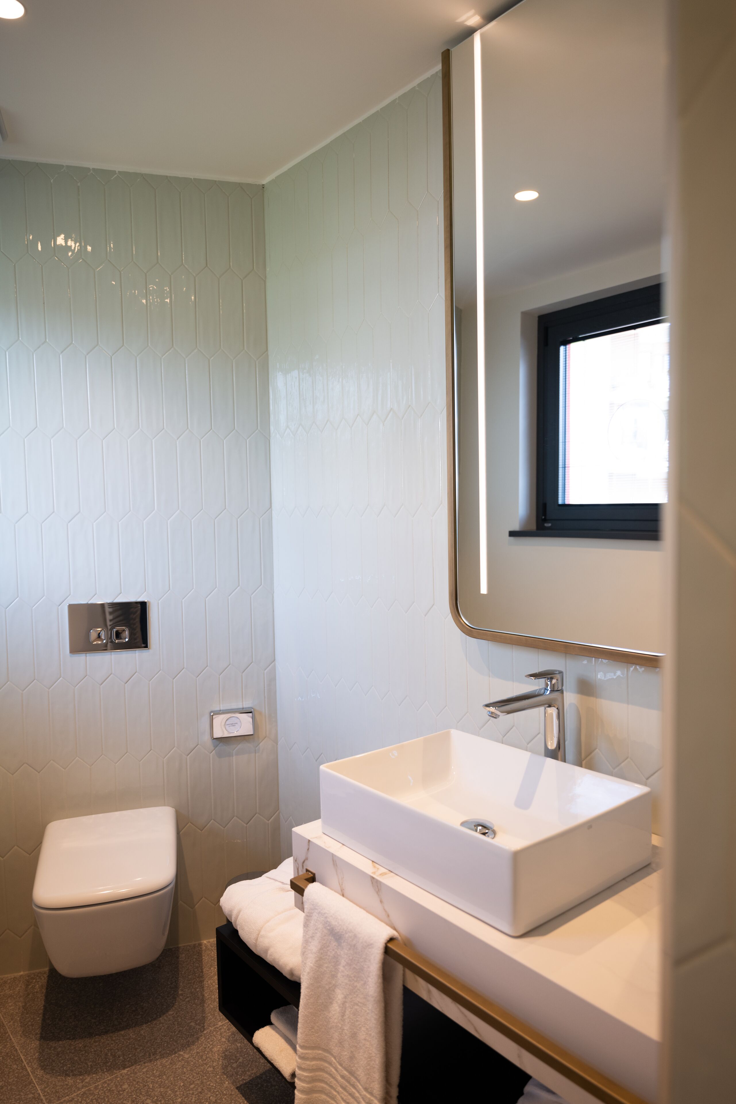 Ein modernes Badezimmer mit Toilette, Waschbecken und einem Spiegel darüber.