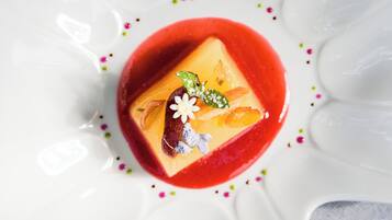 A dessert with a red sauce, a square cake, and decorative elements.