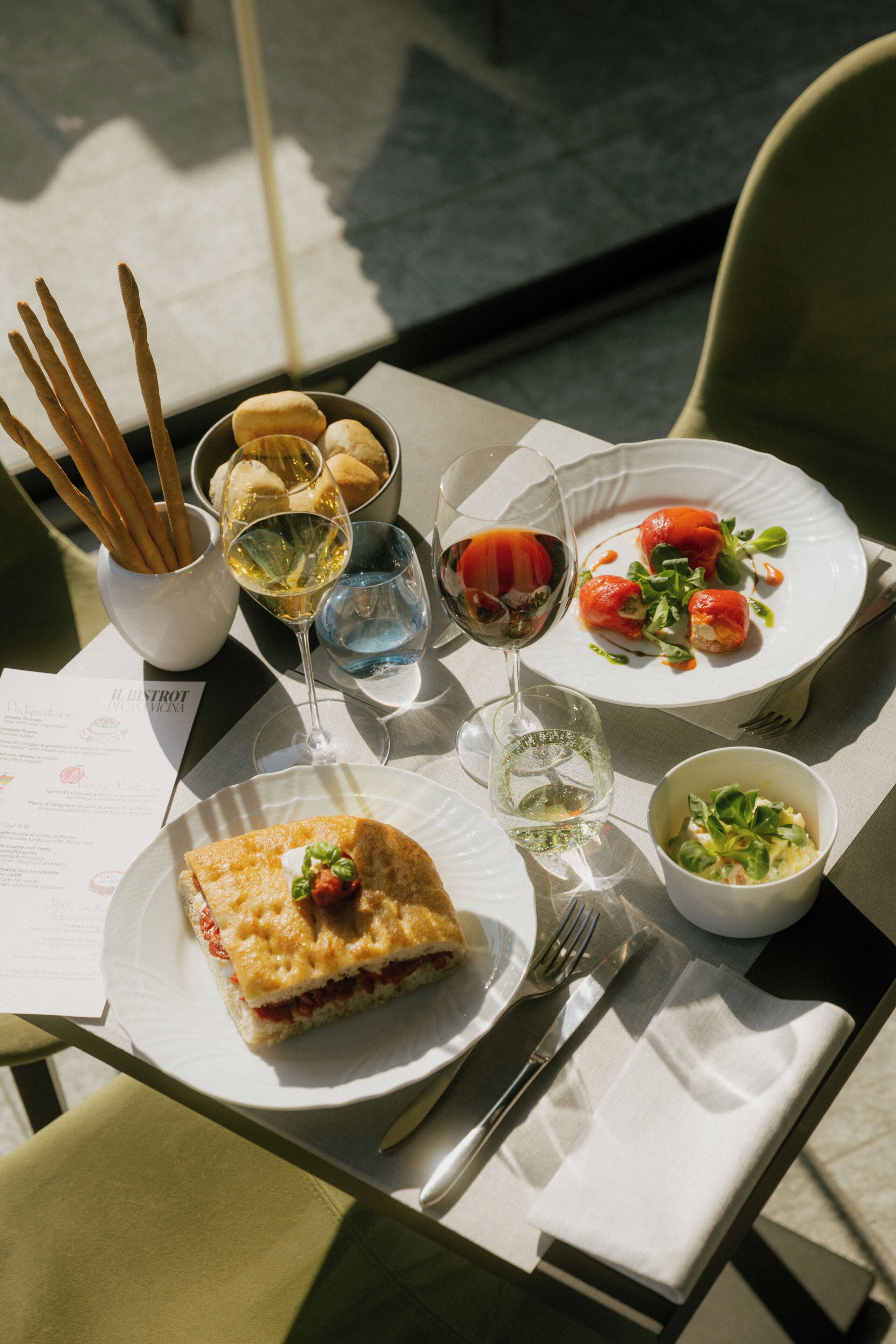 A table with various dishes, glasses of wine, and cutlery.