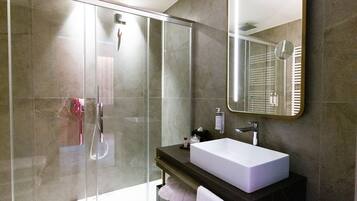 Une salle de bain moderne avec une douche à parois de verre, un grand miroir et un lavabo blanc.