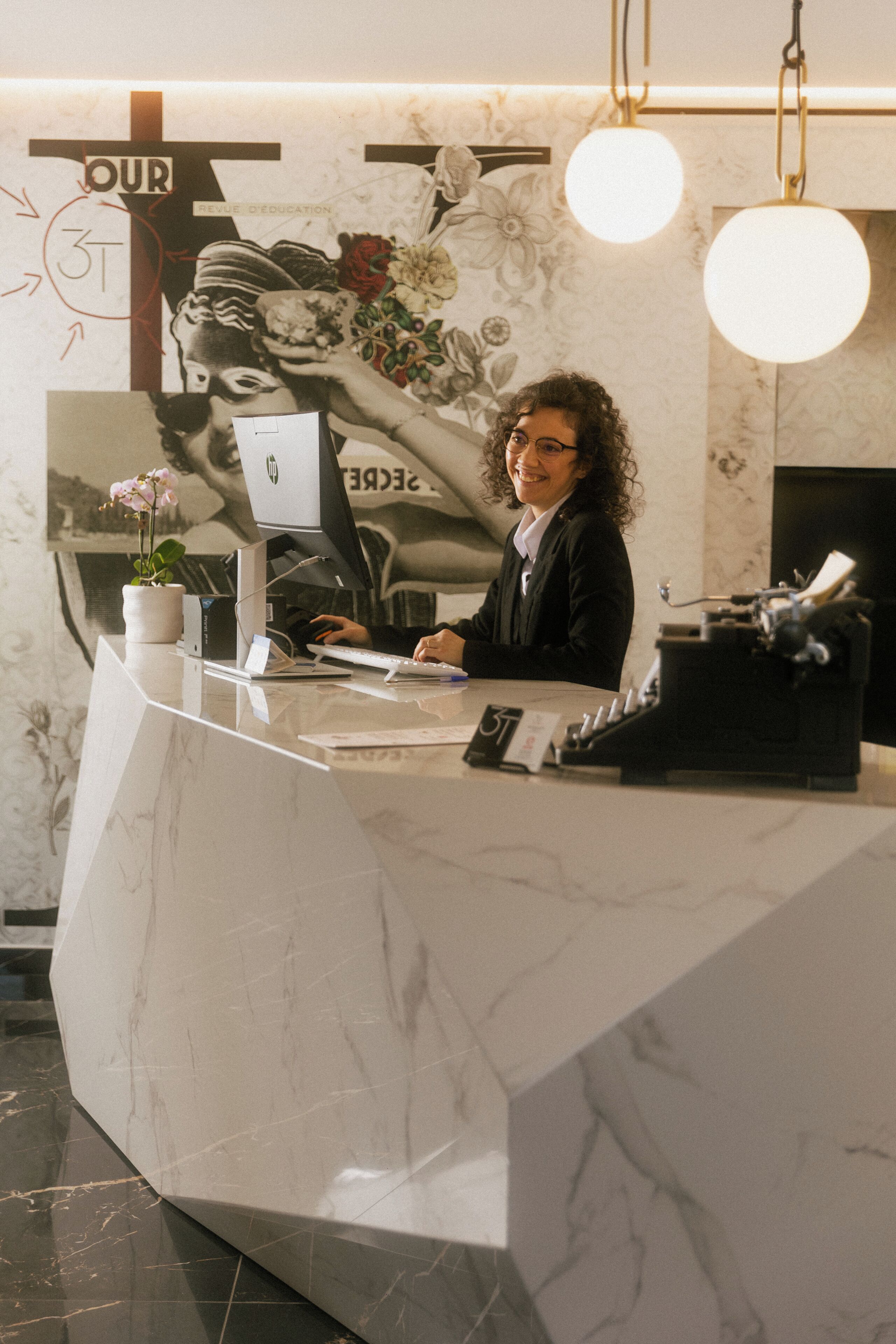 En receptionsdisk med en dator, en telefon och en krukväxt.