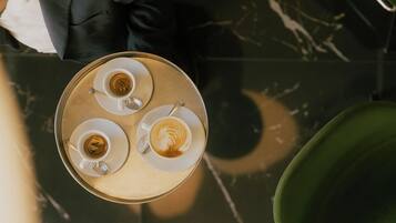 Vista aérea de uma mesa de jantar com três xícaras de café, um suporte e uma cadeira verde.