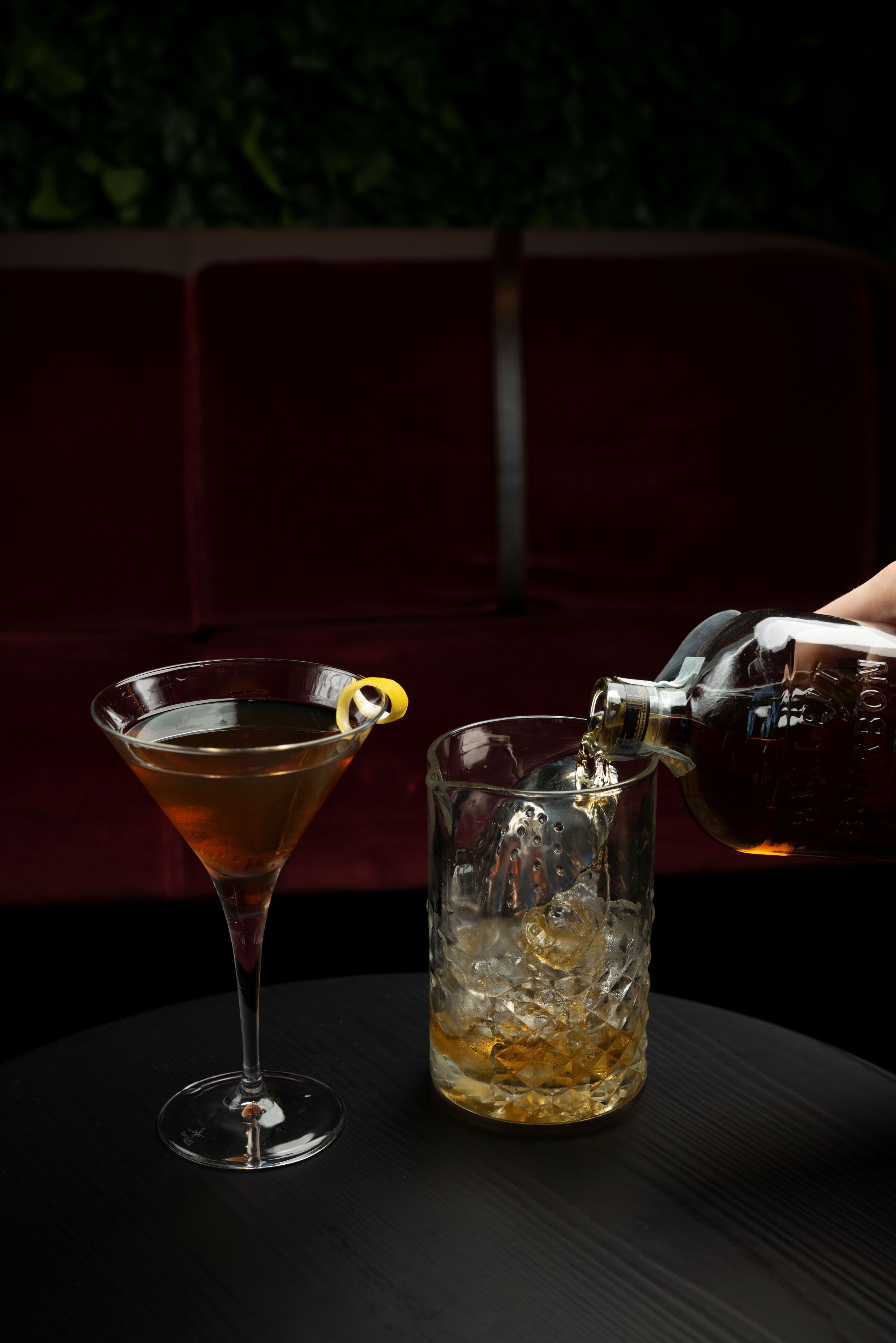 Dos vasos de cóctel, uno de martini y otro de highball, sobre una mesa con fondo oscuro.