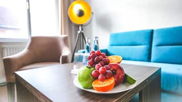 A dining table with a plate of fruit, a lamp, and a blue sofa in the background.