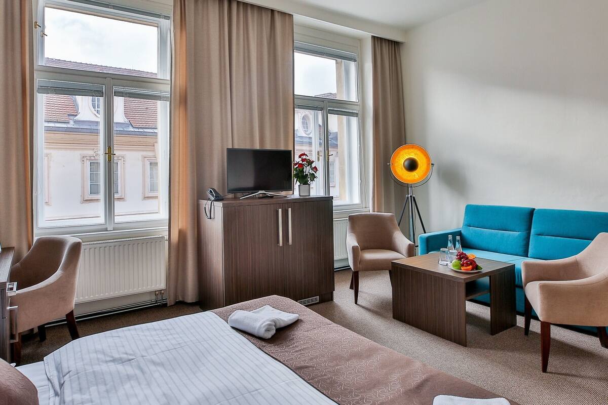 Una habitación de hotel con cama, televisión, escritorio, sofá y lámpara.