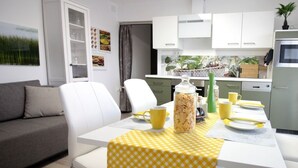 A modern kitchen with white cabinets, a dining table with a yellow checkered tablecloth, and a coffee maker.