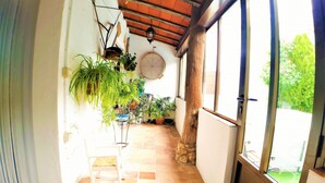 A corridor with tiled flooring, potted plants, a rocking chair, and a wooden pillar. - Beautiful Rural House next to the Júcar river. Rural House Don Alonso (Villalgordo del Jucar)