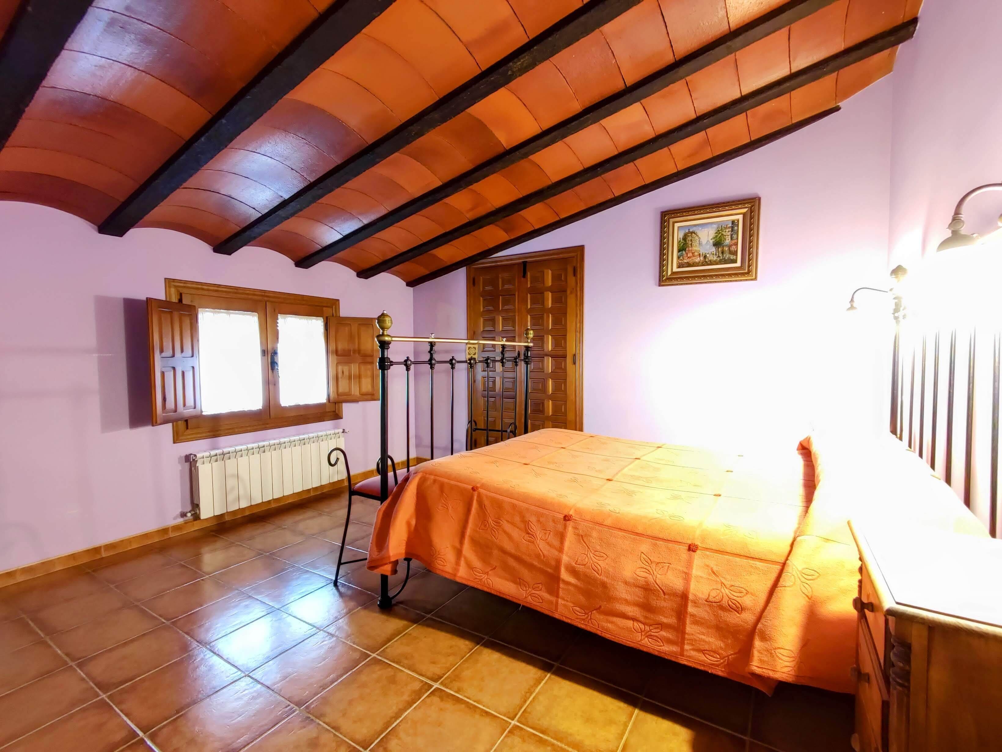 A bedroom with a bed, a window, a radiator, and a door.