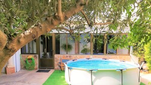 A round swimming pool with a bench in the foreground, surrounded by green artificial turf and trees. - Beautiful Rural House next to the Júcar river. Rural House Don Alonso (Villalgordo del Jucar)