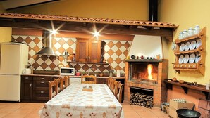 A kitchen with a tiled backsplash, a wood-burning stove, a dining table with chairs, and a refrigerator. - Beautiful Rural House next to the Júcar river. Rural House Don Alonso (Villalgordo del Jucar)