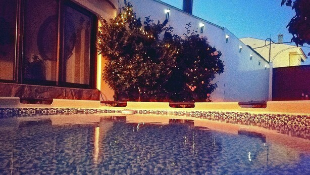 A building with a reflective pool, a large window, and a tree with lights. - Beautiful Rural House next to the Júcar river. Rural House Don Alonso (Villalgordo del Jucar)