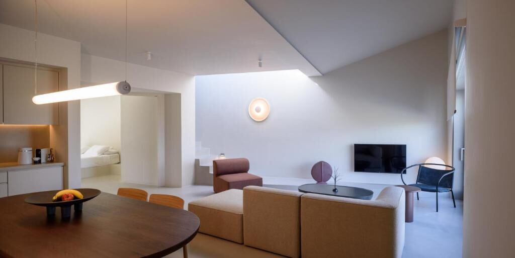 Un salon moderne et bien éclairé, comprenant une table à manger, un canapé et un téléviseur.