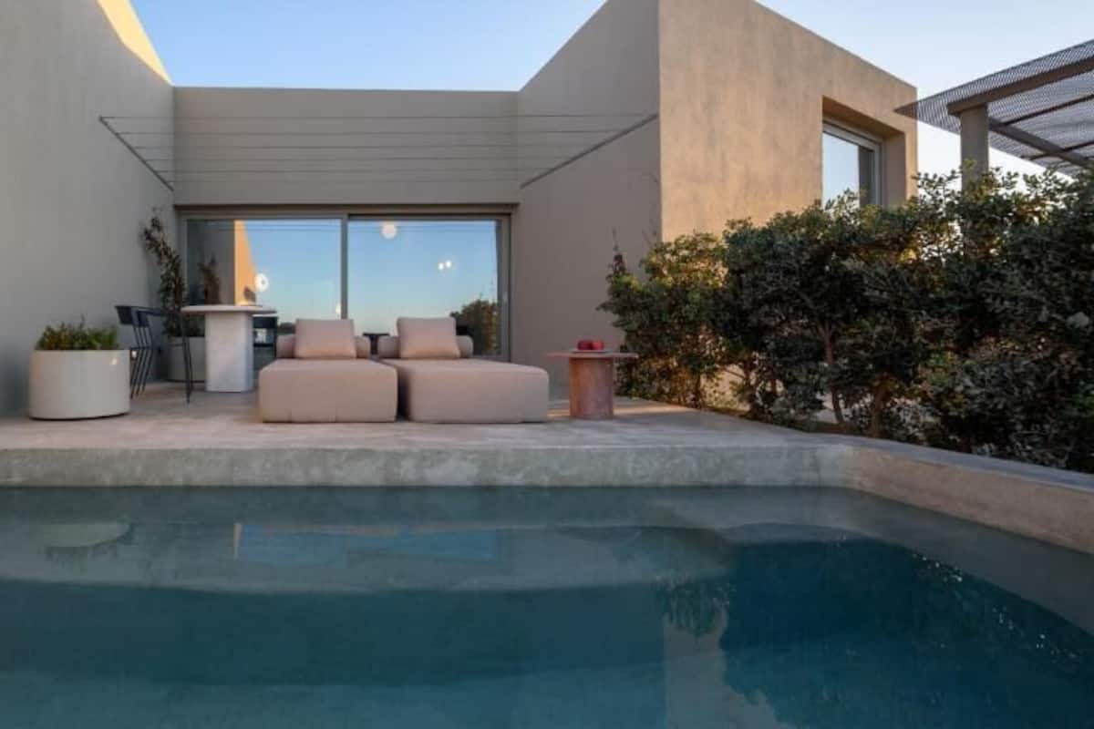 A modern outdoor pool area with a seating arrangement and a large window.
