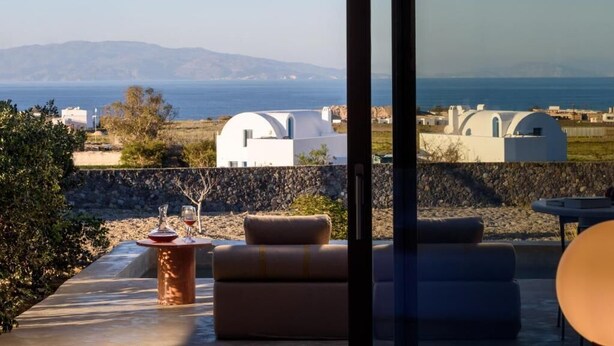 Un área de estar exterior moderna con vistas a edificios blancos y al mar.