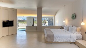 Un dormitorio moderno con una cama grande, televisor integrado y vistas al exterior.