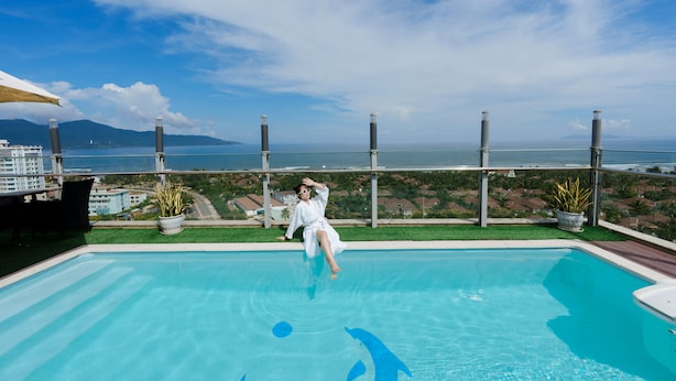 Une piscine offrant une vue dégagée sur l’océan et les montagnes en arrière-plan.