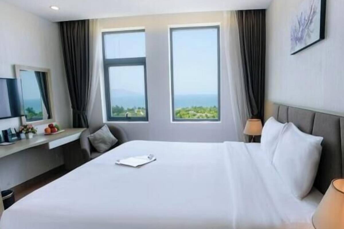 A hotel room with a large bed, a desk, and a view of the outdoors.