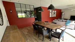 A modern living room with a wooden dining table, a grey sofa, and a red accent wall. - superb villa at the foot of the Pyrenees with swimming pool, large garden (Quillan)