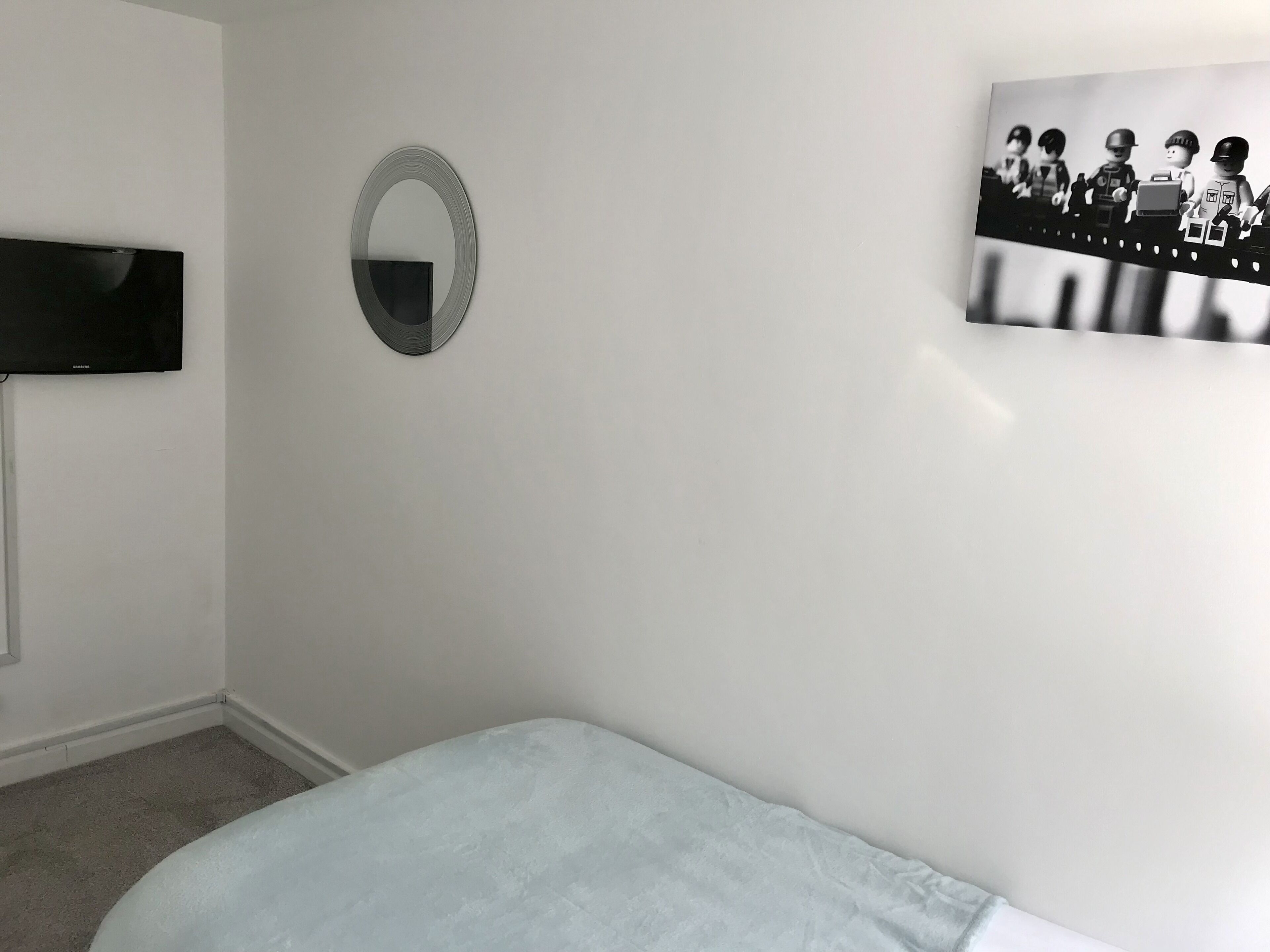 Une chambre à coucher avec un lit, une télévision, un miroir et un tableau au mur.