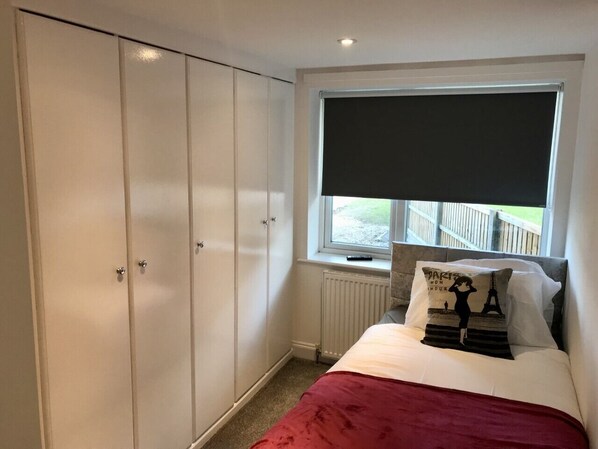 A bedroom with a bed, a window with a view, a radiator, and a wardrobe. - Stanford Villa (Stanford-le-Hope)