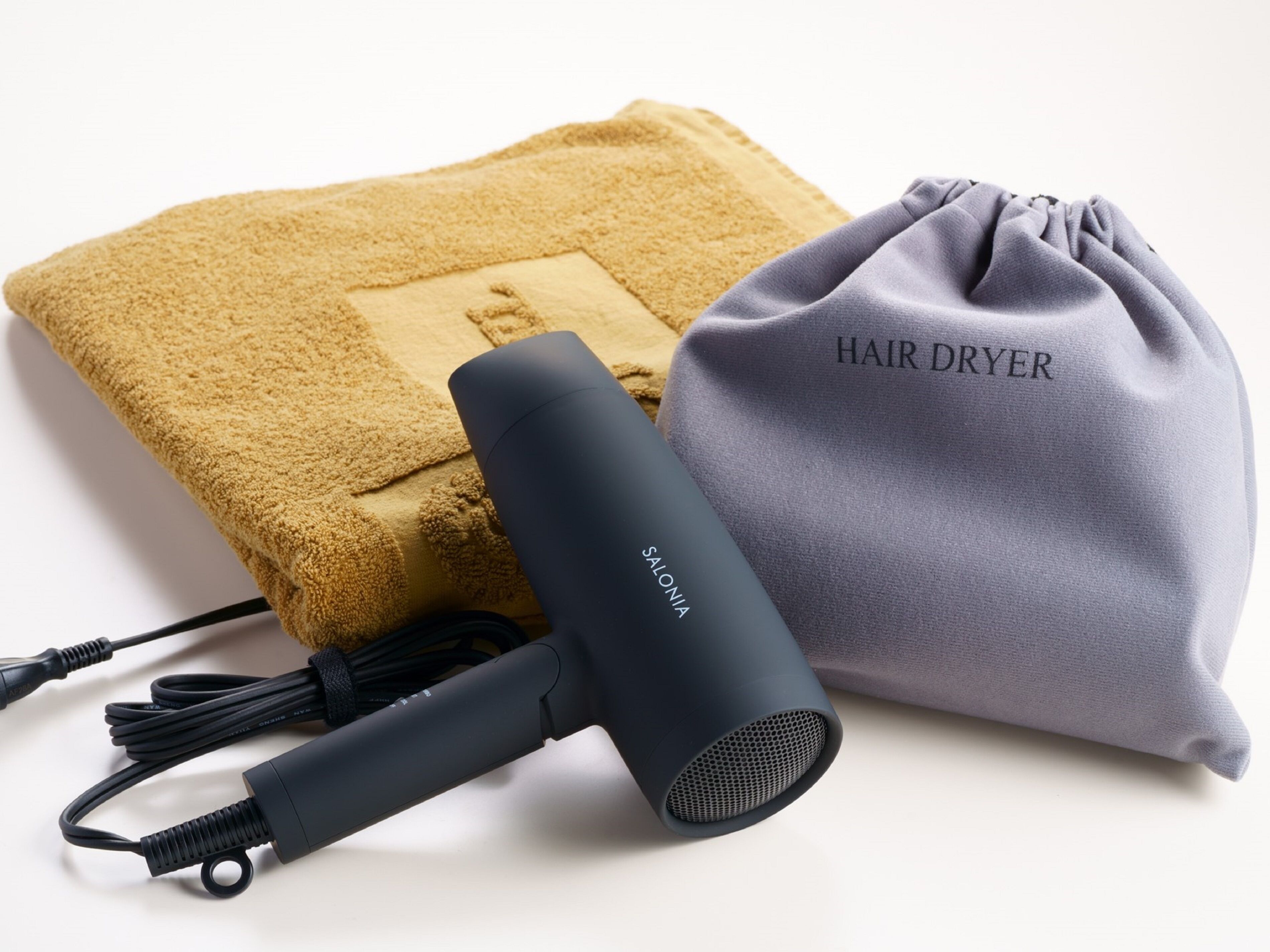 Un secador de pelo, una toalla y una bolsa con cordón que dice "HAIR DRYER".