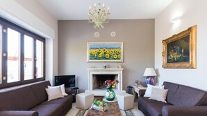 Un salon avec deux canapés, une table basse, une cheminée et un tableau au mur.