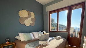 Une chambre à coucher avec un lit, une table de chevet, une lampe et une vue par la fenêtre.