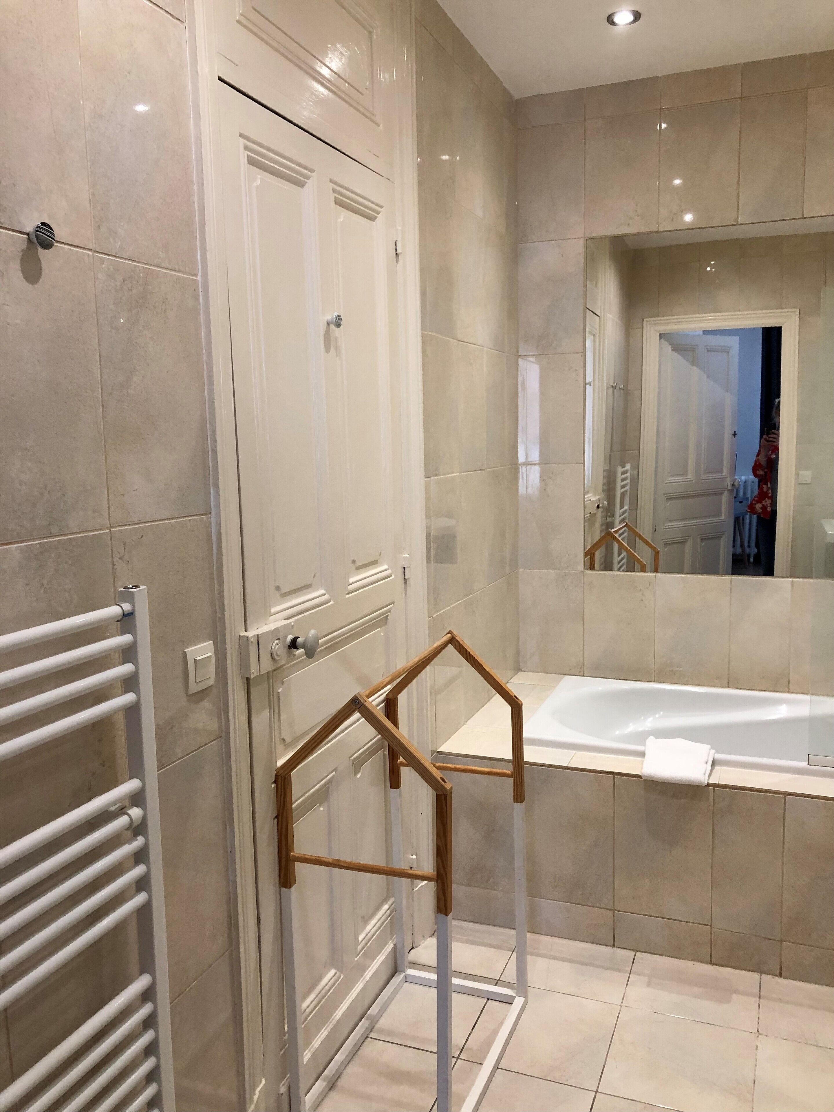 Un baño moderno con bañera, cabina de ducha de vidrio y una toalla blanca colgada en la bañera.