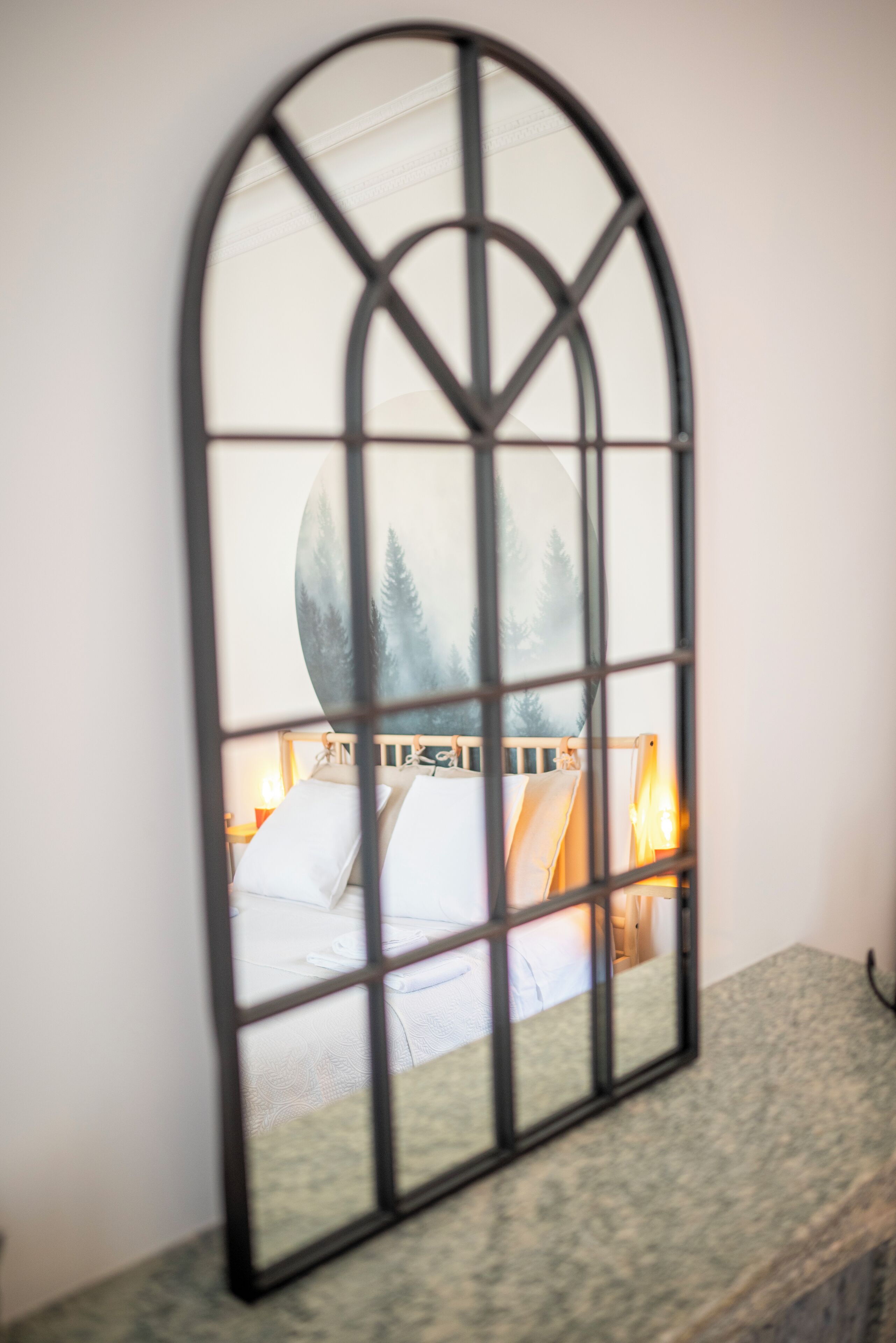 A room with a bed, a nightstand, and a wall-mounted mirror.