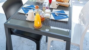 A table set for breakfast with a view of greenery and a stone balustrade.