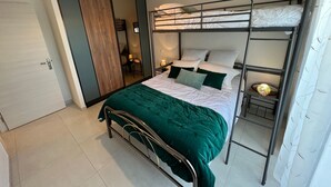 A room with a bunk bed, a green bedspread, a bedside lamp, and a mirror. - Single-storey house Royan 8 pers - Heated swimming pool in summer - Pontaillac beach (VAUX SUR MER)
