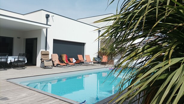 A swimming pool with lounge chairs and a covered patio area. - Single-storey house Royan 8 pers - Heated swimming pool in summer - Pontaillac beach (VAUX SUR MER)