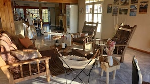 Un salon chaleureux avec une cheminée, des sièges confortables et une grande fenêtre laissant entrer la lumière naturelle.