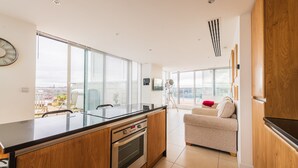 Una cocina moderna con una isla grande, armarios de madera y vistas a la ciudad a través de amplias ventanas.
