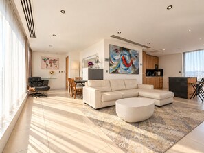 A modern living room with a sectional sofa, a round coffee table, and a dining area with a table and chairs. - 2 Bedroom Penthouse with Parking (Liverpool)