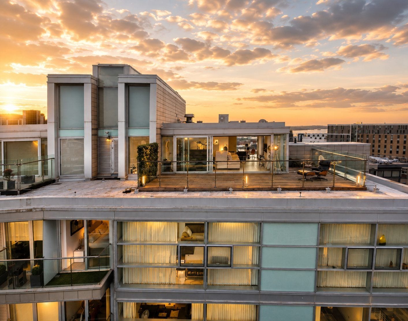 A modern building with multiple floors, large windows, and a rooftop terrace.