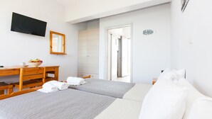 A hotel room with two beds, a desk with a bowl of fruit, a TV, and a mirror. - MariRena plaz (North Kynouria)