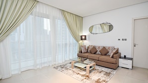 A modern living room with a glass coffee table, a brown sofa, a side table, and a large mirror. - Brand New 1BR Apartment West Avenue Marina - CLN (Dubai)