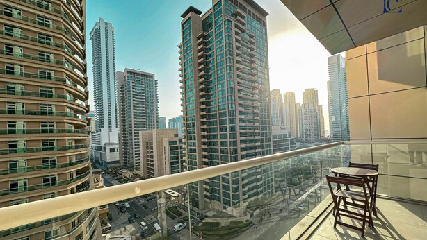 A high-rise building with multiple floors, large windows, and a glass railing overlooking a cityscape. - Brand New 1BR Apartment West Avenue Marina - CLN (Dubai)