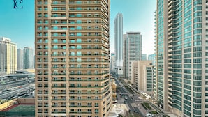 A high-rise building with multiple balconies, a pedestrian walkway, and a road with vehicles. - Brand New 1BR Apartment West Avenue Marina - CLN (Dubai)