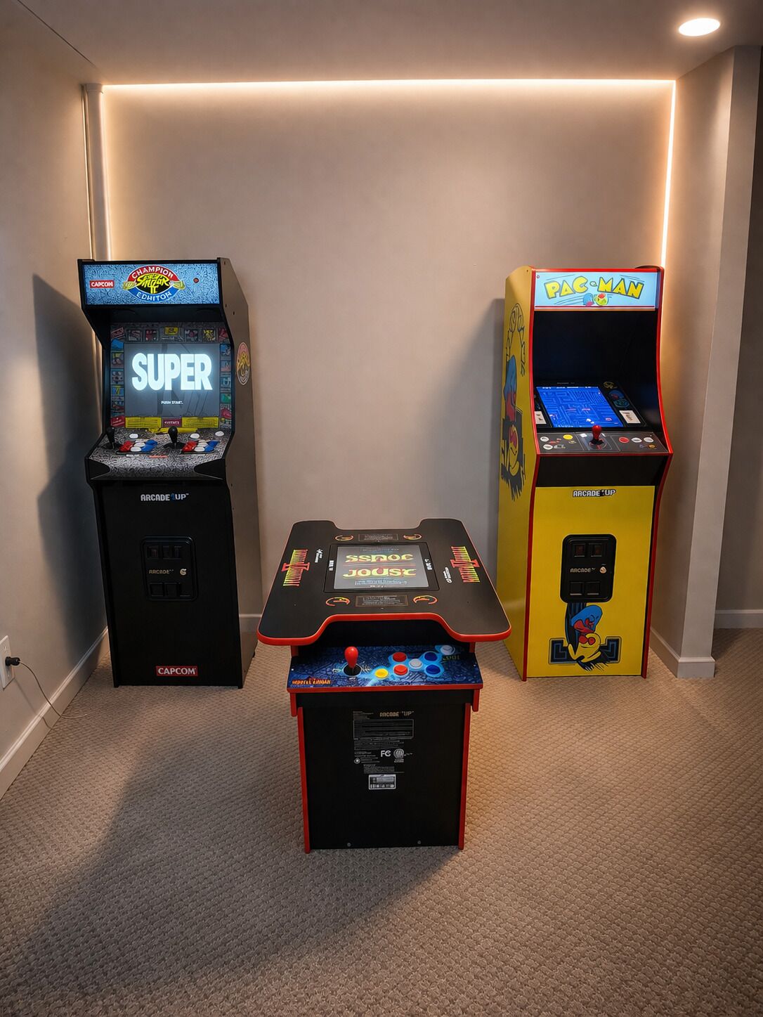 Three arcade machines in a room with carpeted flooring and a plain wall.
