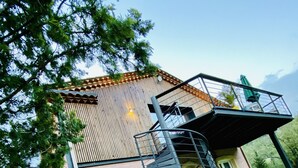 A building with a wooden exterior, a staircase leading to a balcony, and a gravel path in front. - NO, AVAILABLE AD BEING REMOVED (Ceilhes-et-Rocozels)